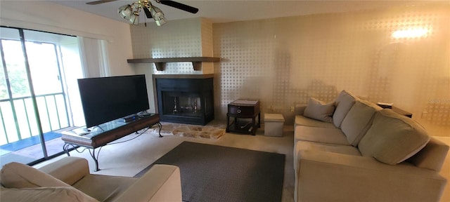 living room featuring a large fireplace, ceiling fan, and carpet floors