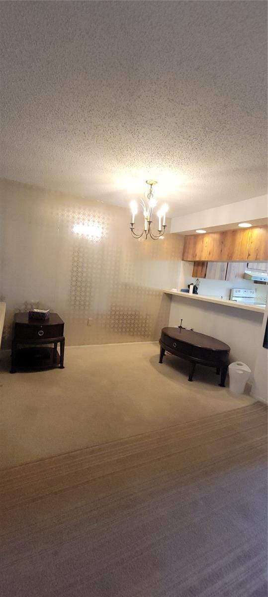 unfurnished bedroom with a textured ceiling, carpet flooring, and an inviting chandelier