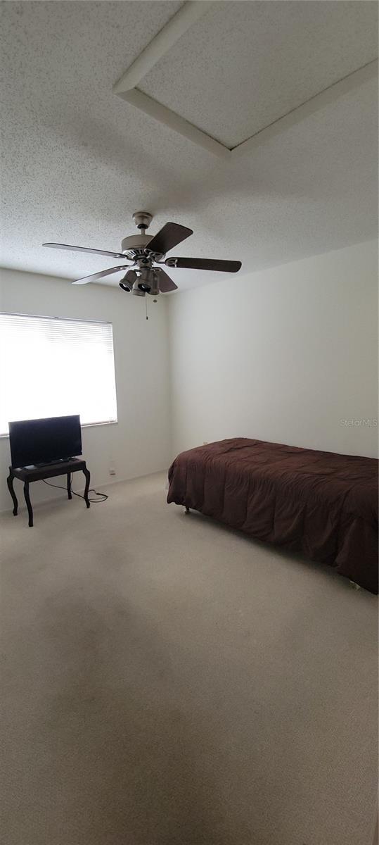 unfurnished bedroom with a textured ceiling, ceiling fan, and carpet