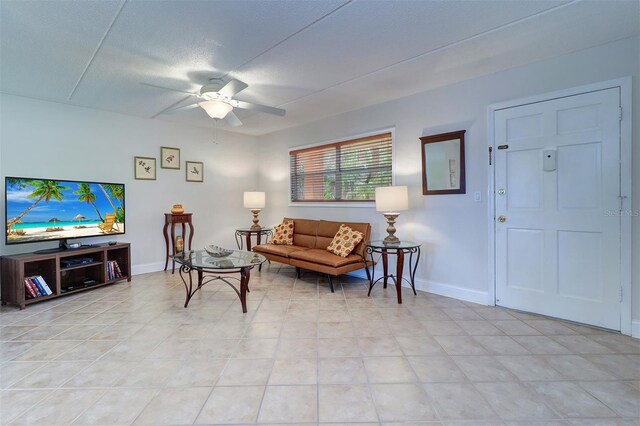 living room with a textured ceiling, light tile patterned flooring, and ceiling fan