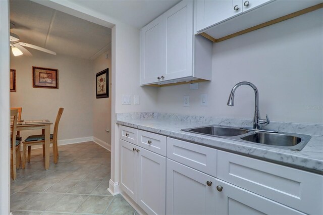 kitchen featuring white cabinets, light stone counters, sink, and ceiling fan