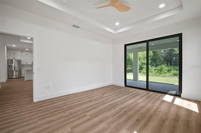 spare room with a tray ceiling, hardwood / wood-style floors, and ceiling fan