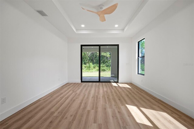 spare room with a tray ceiling and wood-type flooring