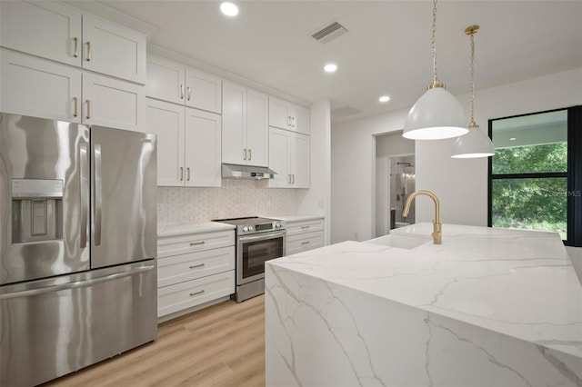 kitchen featuring stainless steel appliances, light stone countertops, white cabinets, and decorative light fixtures