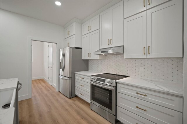 kitchen with light stone countertops, appliances with stainless steel finishes, decorative backsplash, light wood-type flooring, and white cabinets