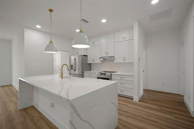 kitchen featuring pendant lighting, an island with sink, appliances with stainless steel finishes, white cabinets, and light hardwood / wood-style floors