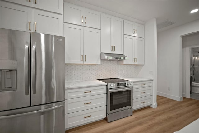 kitchen with light wood-type flooring, white cabinetry, light stone counters, decorative backsplash, and appliances with stainless steel finishes