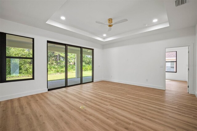 empty room featuring ceiling fan, hardwood / wood-style flooring, and a raised ceiling