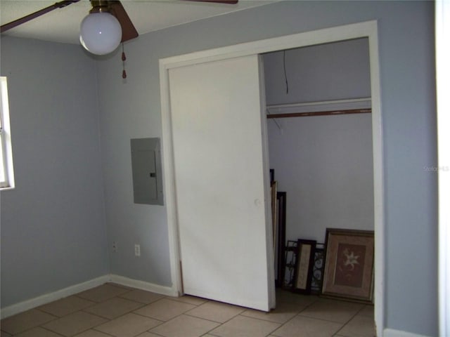 unfurnished bedroom with electric panel, a closet, ceiling fan, and light tile patterned floors