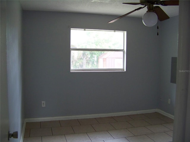 tiled empty room featuring ceiling fan and a textured ceiling