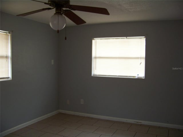 tiled spare room featuring ceiling fan