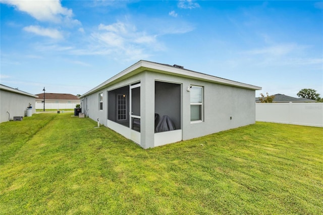 rear view of house with a lawn and a sunroom