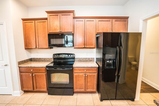 kitchen with black appliances, light hardwood / wood-style flooring, and light stone countertops