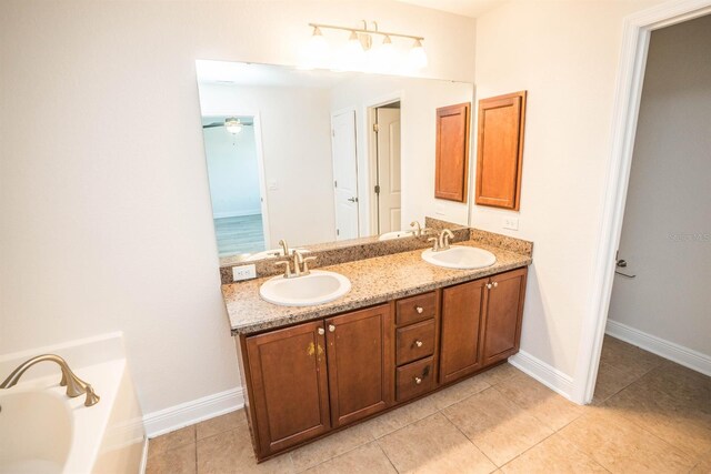 bathroom with tile patterned floors, a tub to relax in, and vanity