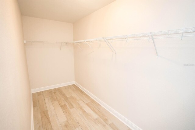 walk in closet with light hardwood / wood-style floors