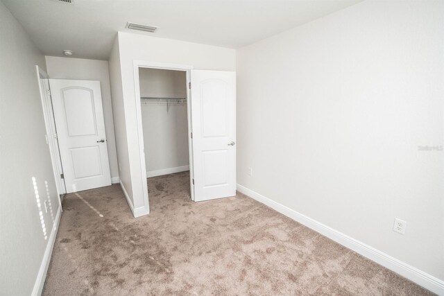 unfurnished bedroom with light colored carpet and a closet