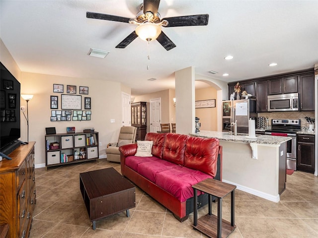 living room featuring ceiling fan, sink, and light tile patterned floors