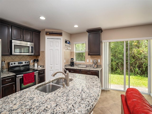 kitchen with dark brown cabinetry, stainless steel appliances, sink, and decorative backsplash