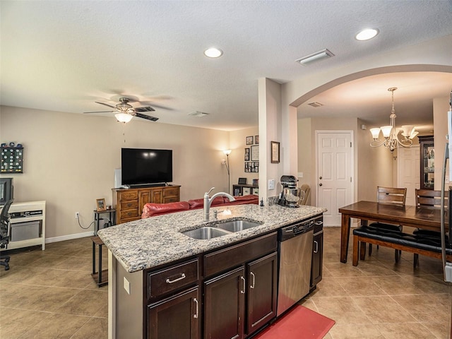 kitchen featuring pendant lighting, ceiling fan with notable chandelier, an island with sink, sink, and stainless steel dishwasher