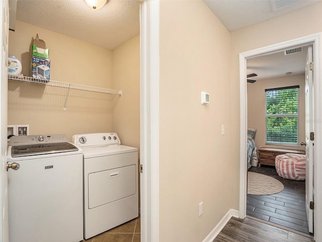 laundry area featuring dark wood-type flooring, a textured ceiling, and washer and dryer