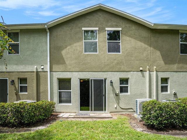 rear view of house with ac unit and a lawn