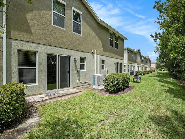 back of property with a lawn and ac unit