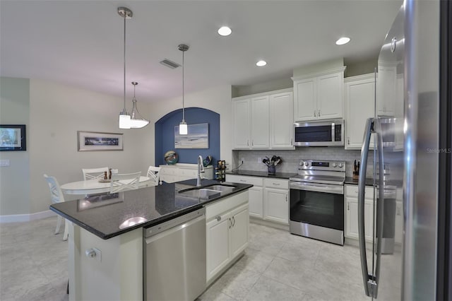 kitchen featuring white cabinetry, sink, stainless steel appliances, an island with sink, and pendant lighting