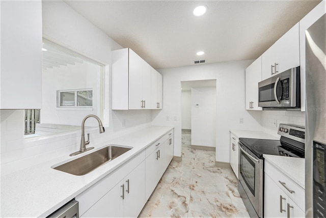 kitchen featuring white cabinetry, appliances with stainless steel finishes, sink, and backsplash