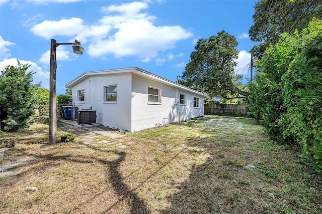 rear view of house featuring central AC and a yard