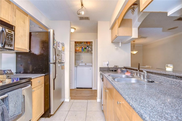 kitchen with light brown cabinetry, hanging light fixtures, stainless steel appliances, sink, and a textured ceiling