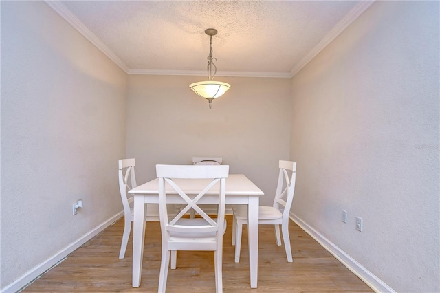 dining room featuring baseboards, a textured ceiling, crown molding, and light wood-type flooring