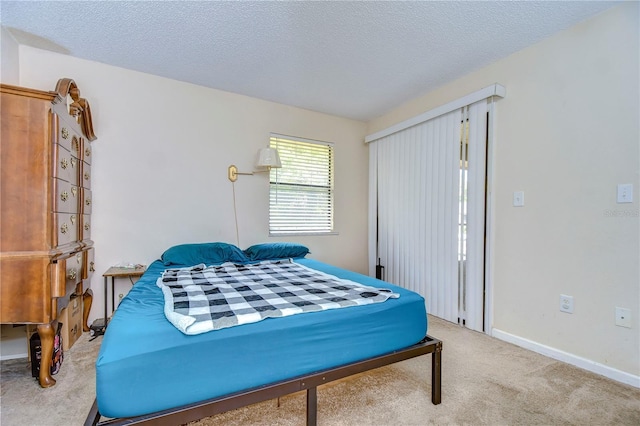 bedroom with baseboards, a textured ceiling, and carpet