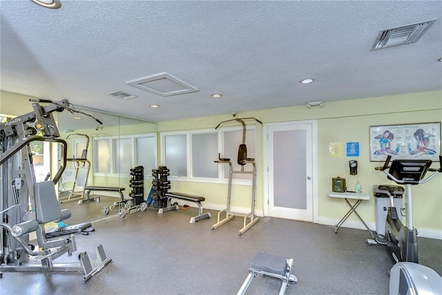 gym featuring baseboards, a textured ceiling, and visible vents