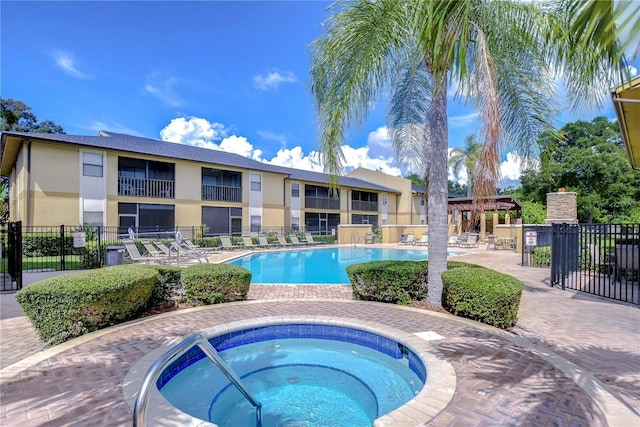community pool featuring a patio, fence, and a hot tub