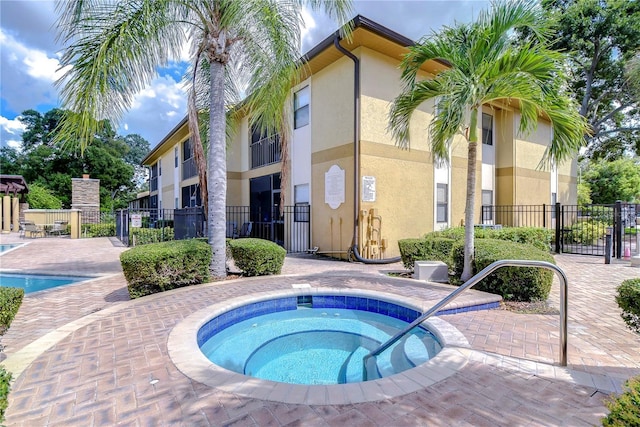pool featuring a community hot tub, a patio area, and fence