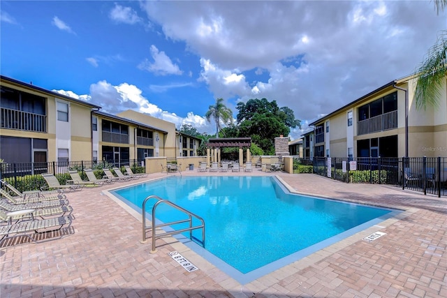 pool with a patio, fence, and a pergola