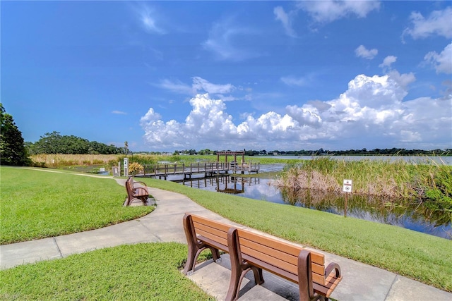 dock area with a lawn and a water view