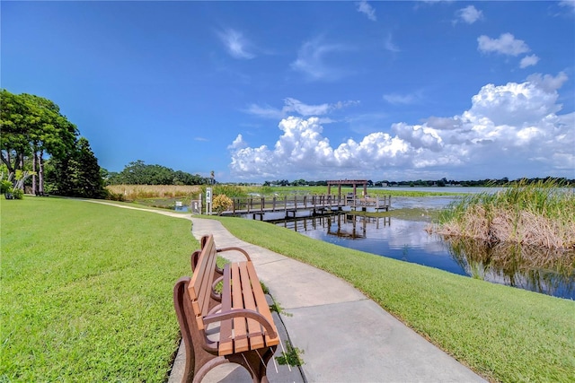 view of dock with a water view and a yard