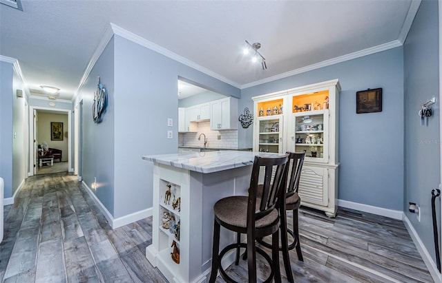 kitchen featuring a kitchen breakfast bar, decorative backsplash, dark hardwood / wood-style floors, and white cabinets