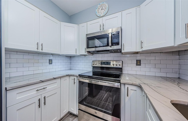 kitchen featuring appliances with stainless steel finishes, decorative backsplash, and white cabinets