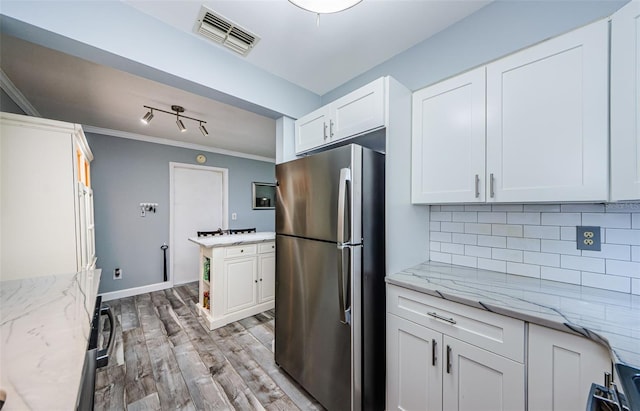 kitchen featuring light stone countertops, light wood-type flooring, white cabinetry, and stainless steel fridge