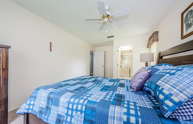 bedroom featuring ceiling fan, a textured ceiling, carpet floors, and connected bathroom