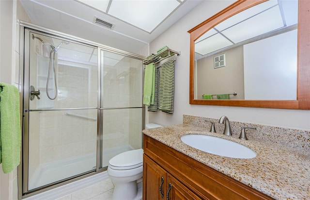 bathroom with tile patterned floors, a shower with door, vanity, and toilet