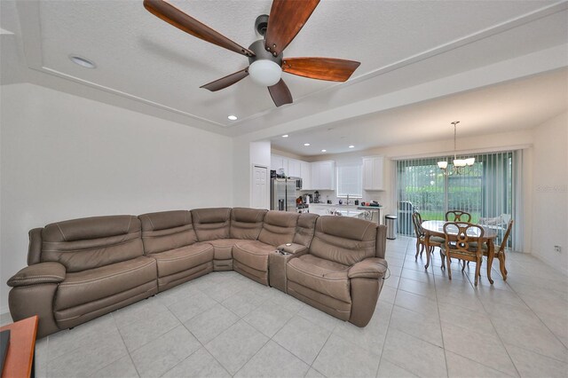 living room featuring ceiling fan with notable chandelier, a textured ceiling, and light tile patterned floors