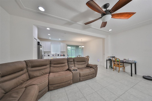 living room with a textured ceiling, ceiling fan with notable chandelier, and light tile patterned flooring