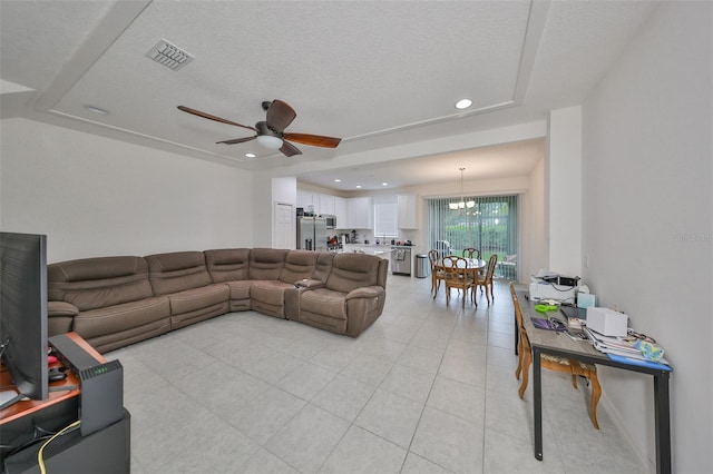 tiled living room featuring ceiling fan with notable chandelier and a textured ceiling