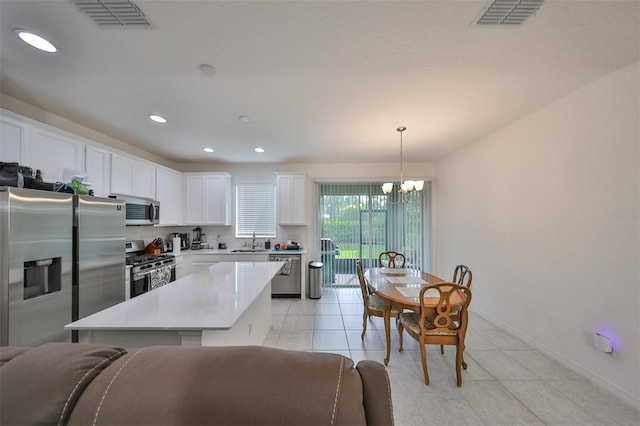 kitchen featuring a notable chandelier, appliances with stainless steel finishes, a center island, sink, and white cabinetry