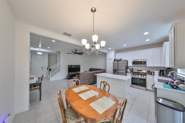 dining space featuring ceiling fan with notable chandelier, sink, and light tile patterned flooring