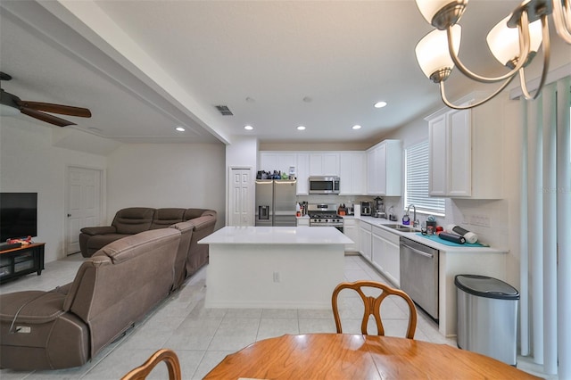 kitchen featuring stainless steel appliances, light tile patterned floors, a kitchen island, sink, and white cabinets