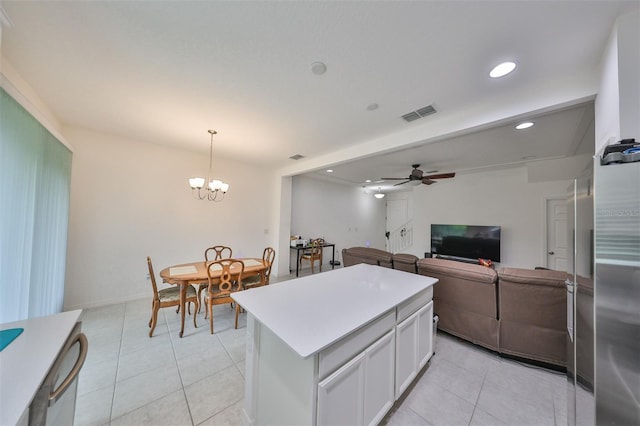 kitchen with ceiling fan with notable chandelier, light tile patterned floors, a center island, hanging light fixtures, and white cabinetry